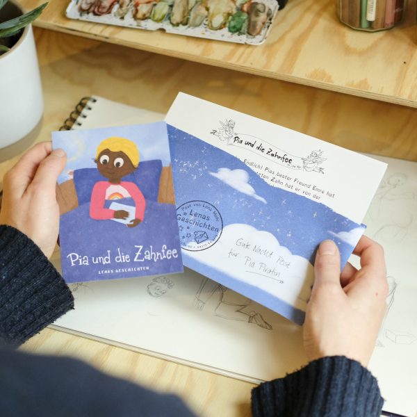 Foto: Zwei Hände halten einen blauen Briefumschlag mit Wolken, aus dem ein Brief guckt, sowie eine Karte